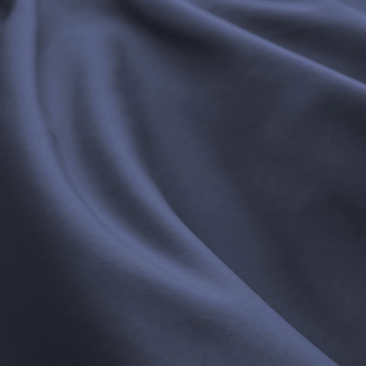 Macro shot of deep navy high-thread-count sateen cotton highlighting lustrous finish