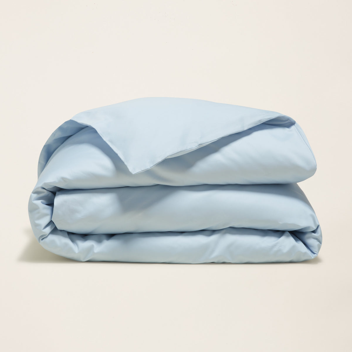 Folded light blue sateen duvet cover on clean white background
