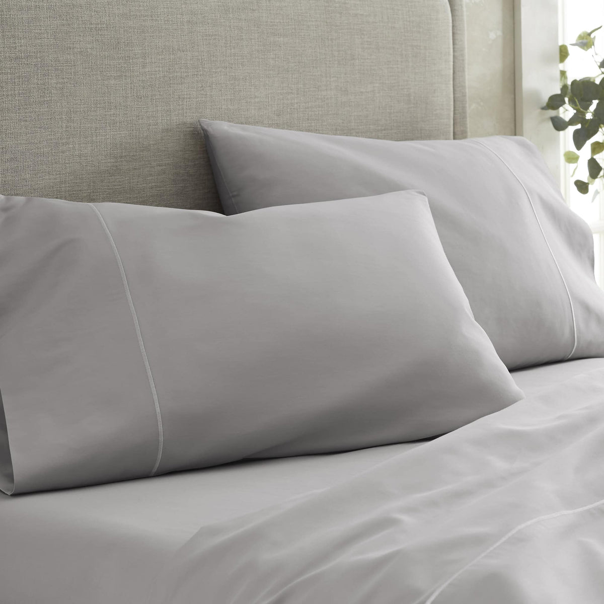 Grey pillowcases with contrast piping on textured beige headboard