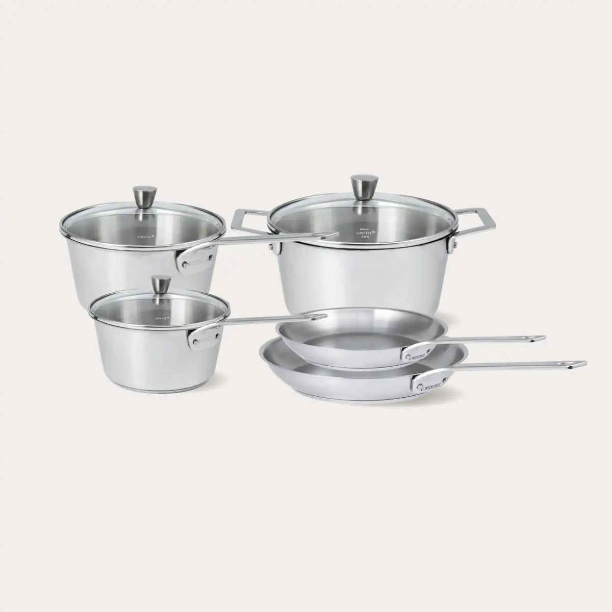 Nested brushed stainless steel saucepans with glass lids against white background
