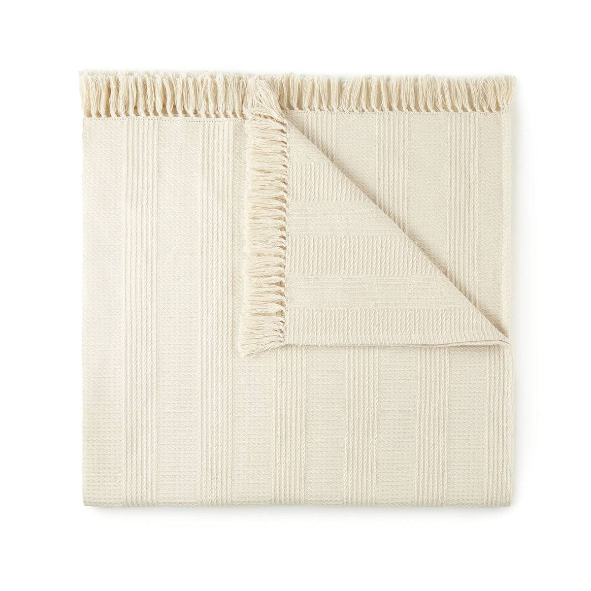 Folded cream organic cotton throw with waffle weave texture and tassels on white background