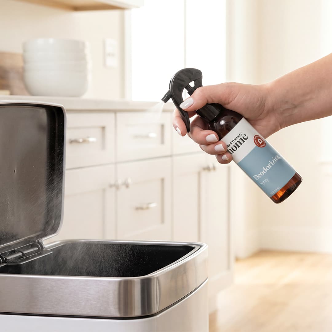 Hand spraying solution into stainless steel kitchen trash can interior