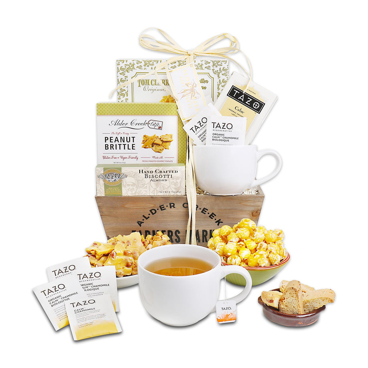 White background display of wooden crate, amber tea in mug, golden popcorn bowl, almond biscotti plate, and fanned tea