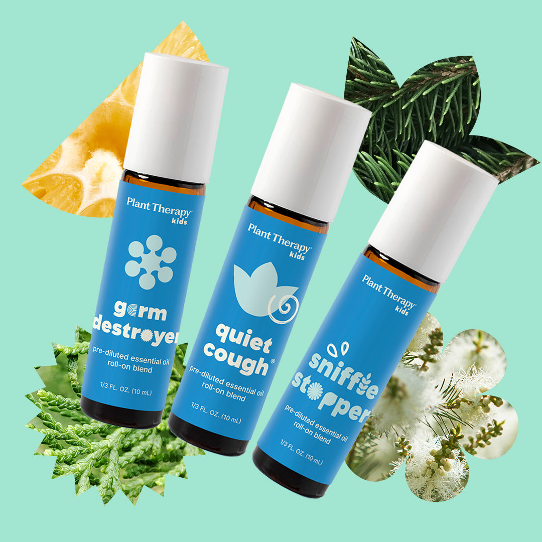 Three labeled essential oil bottles arranged diagonally on mint green surrounded by citrus slices and pine needles.