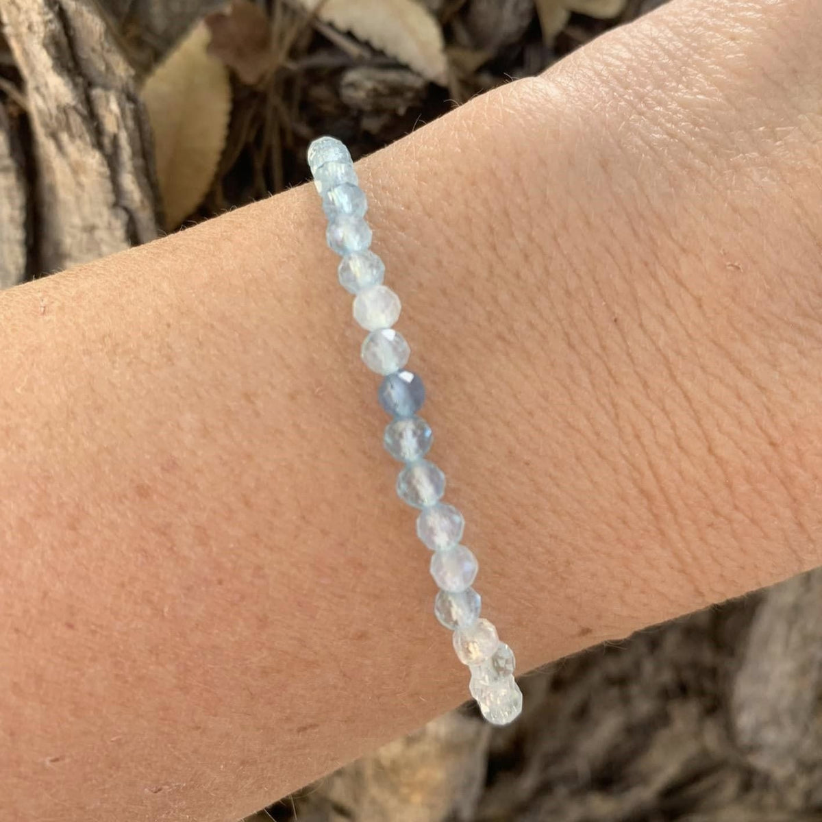 Delicate pale blue bead bracelet draped over wrist in natural light