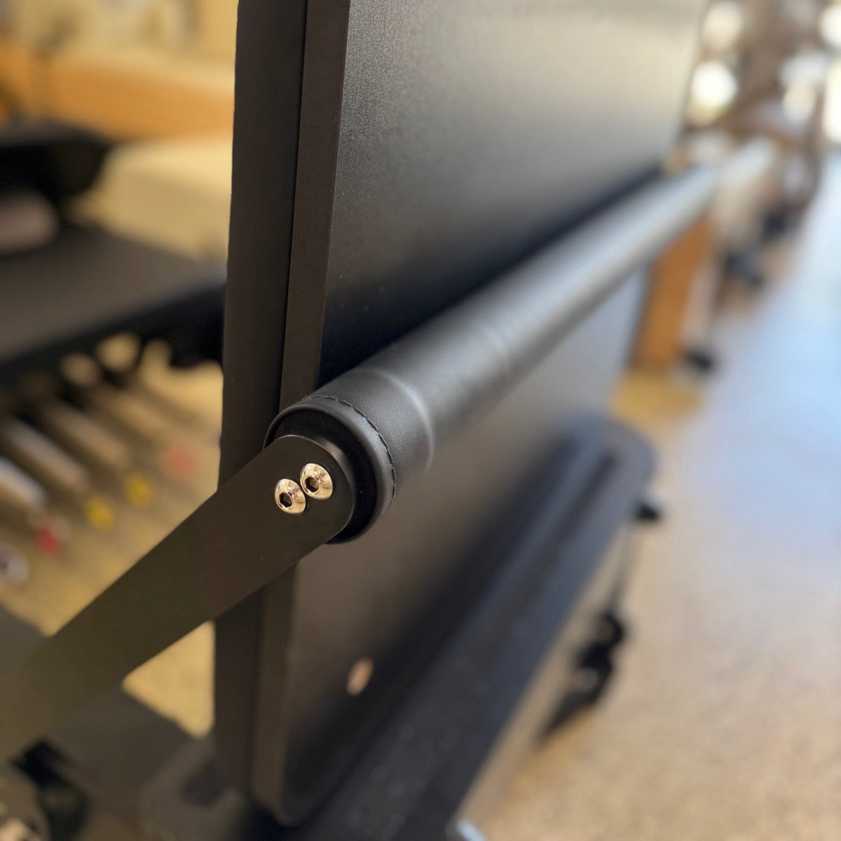 Detail of robust black metal frame construction featuring cylindrical padded roller with visible stitching on leather-like