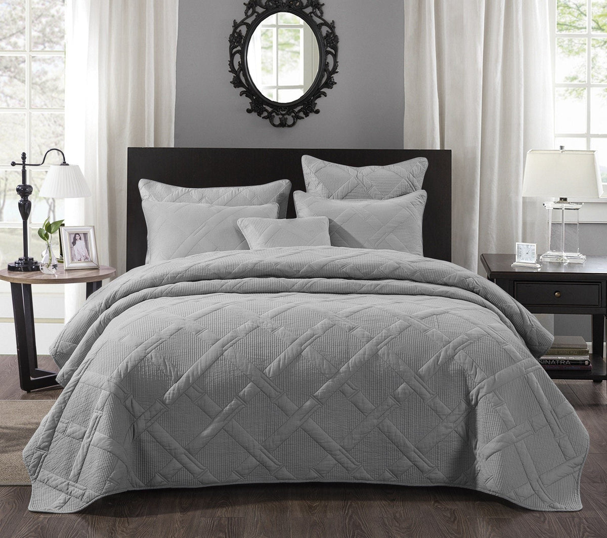 Light gray quilted bedspread with geometric diamond stitch on a dark wood headboard bed, featuring matching pillow shams in a