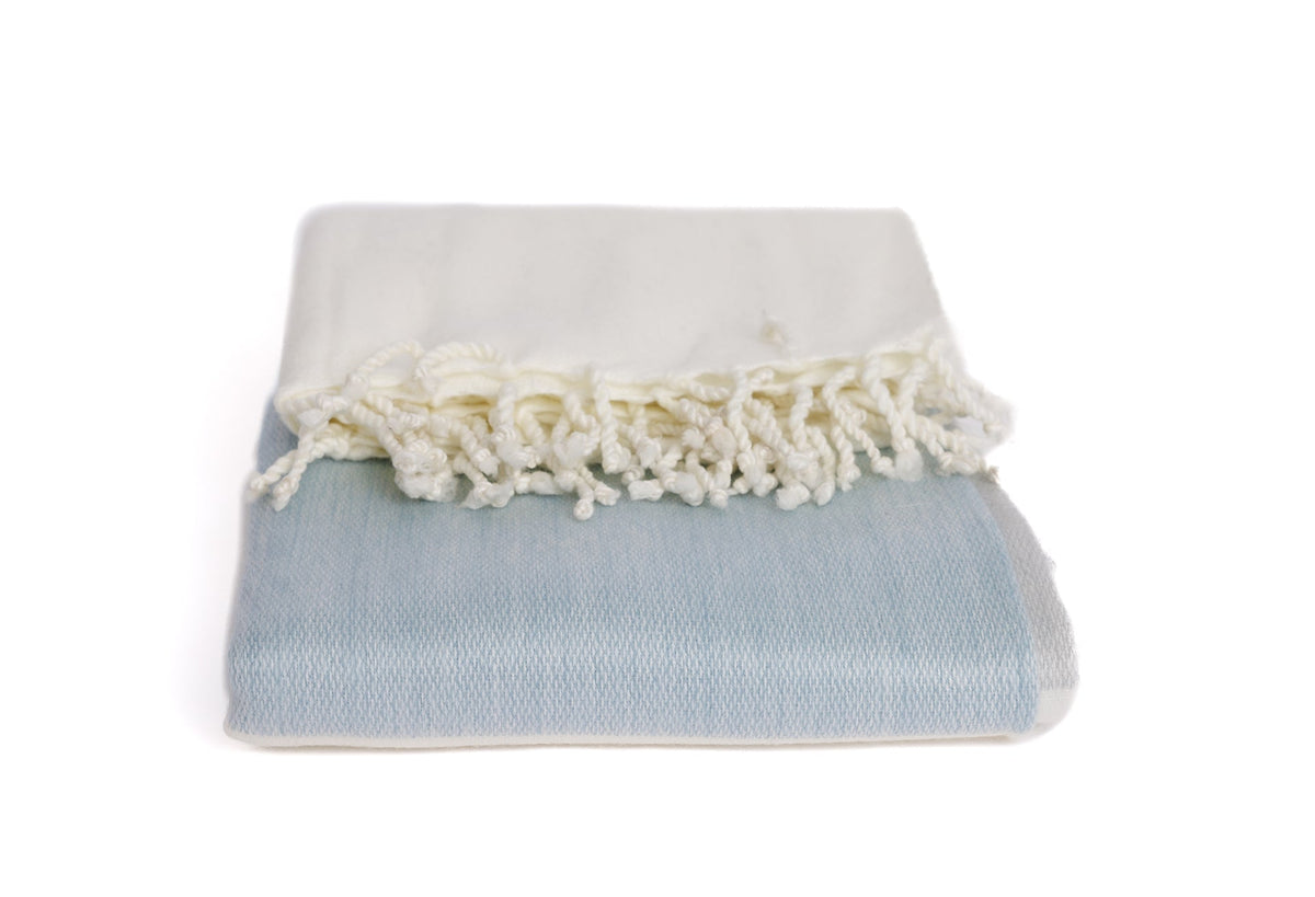 Close-up of folded alpaca blanket showing woven texture and cotton fringe detail