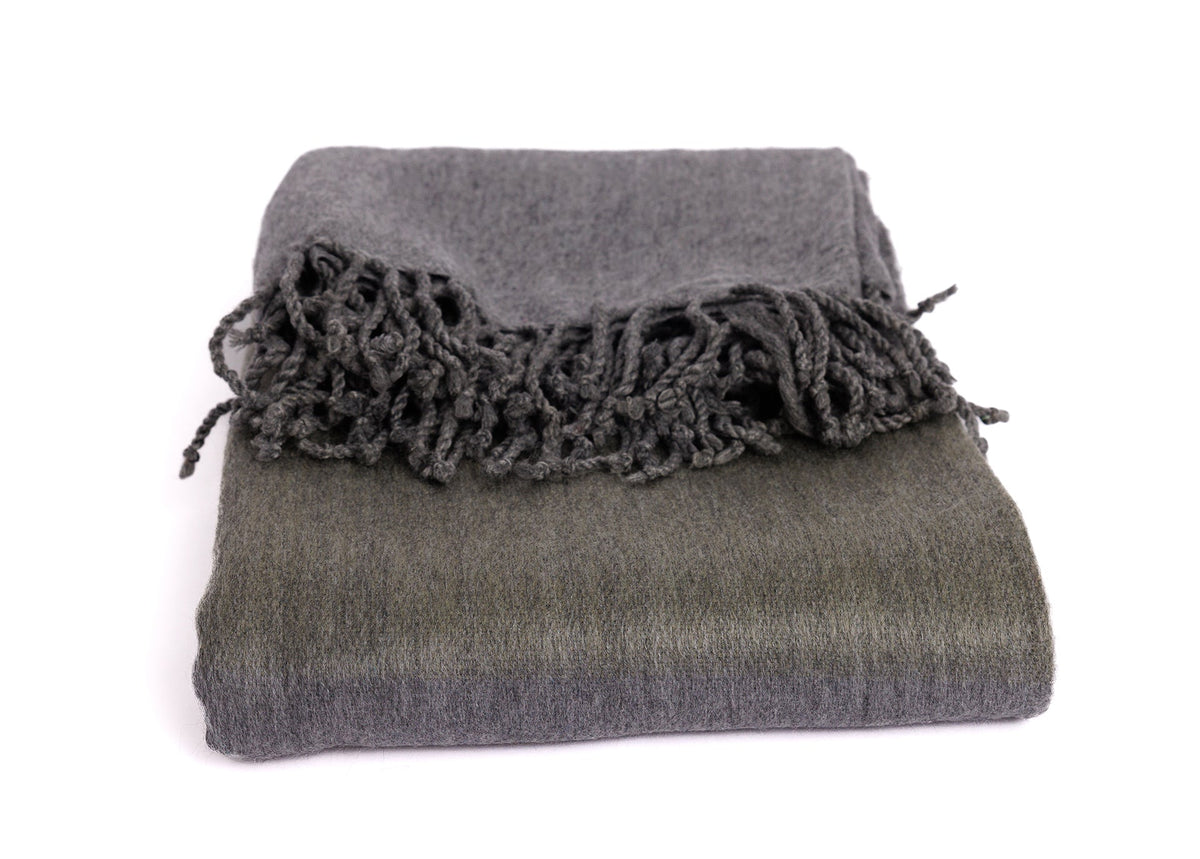 Angle of folded alpaca blanket showcasing depth of charcoal and olive color blocks with intricate knotting
