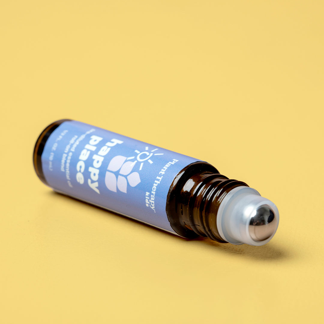 Close-up of amber bottle lying horizontally on yellow surface revealing silver metal rollerball tip and removed white cap