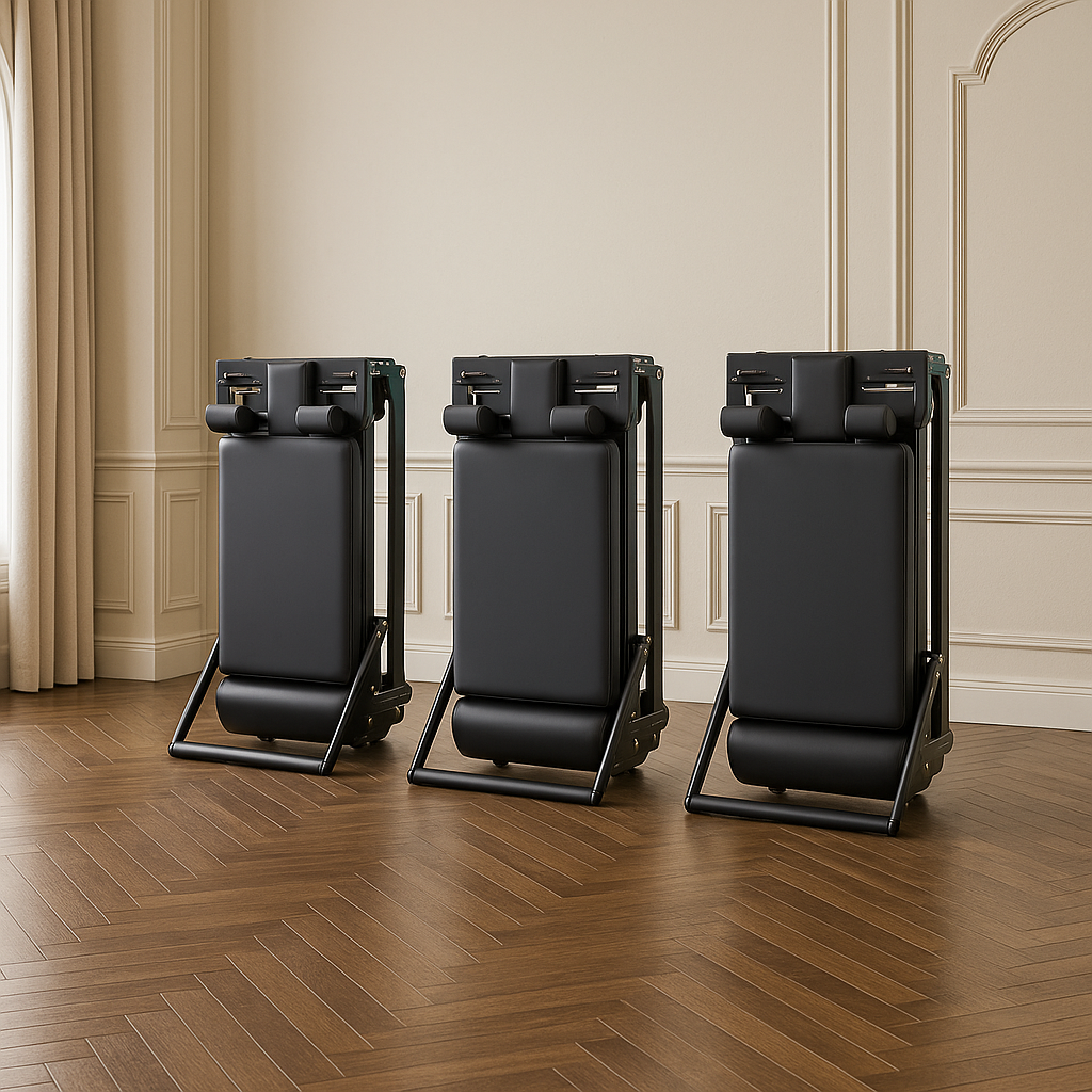 Three black Pilates reformers folded vertically in compact standing position to highlight space-saving storage design