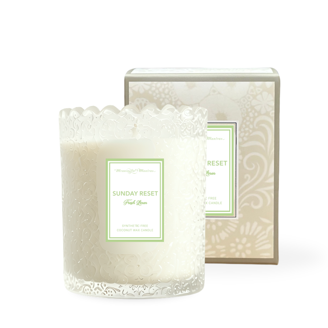 White frosted glass candle with embossed floral pattern and scalloped rim beside beige damask box