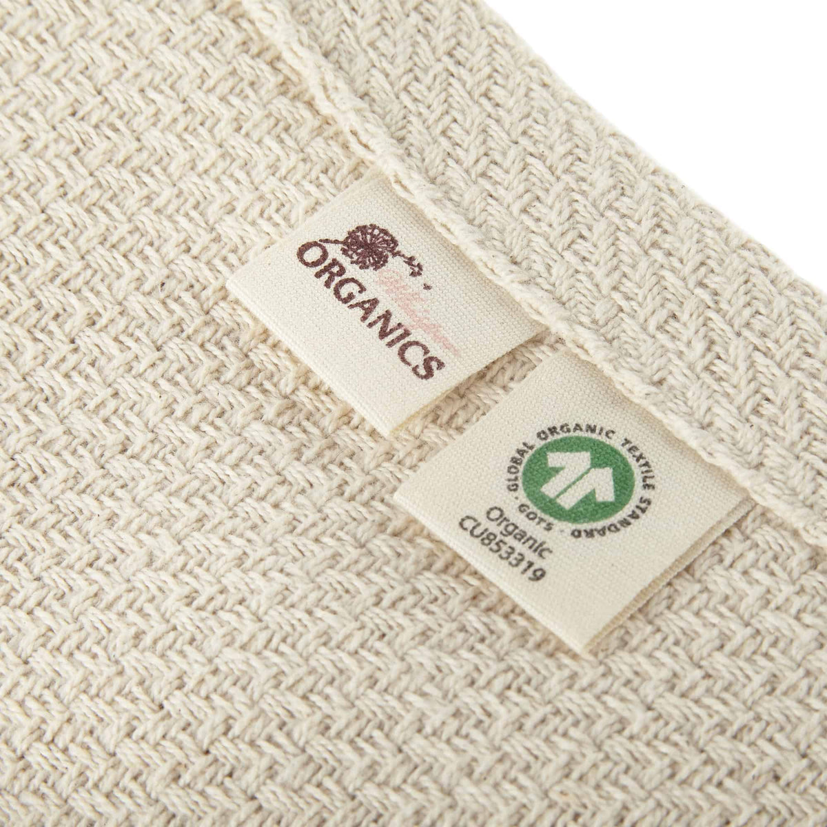 Close-up of blanket corner showing Whisper Organics logo and green GOTS certification label CU853319