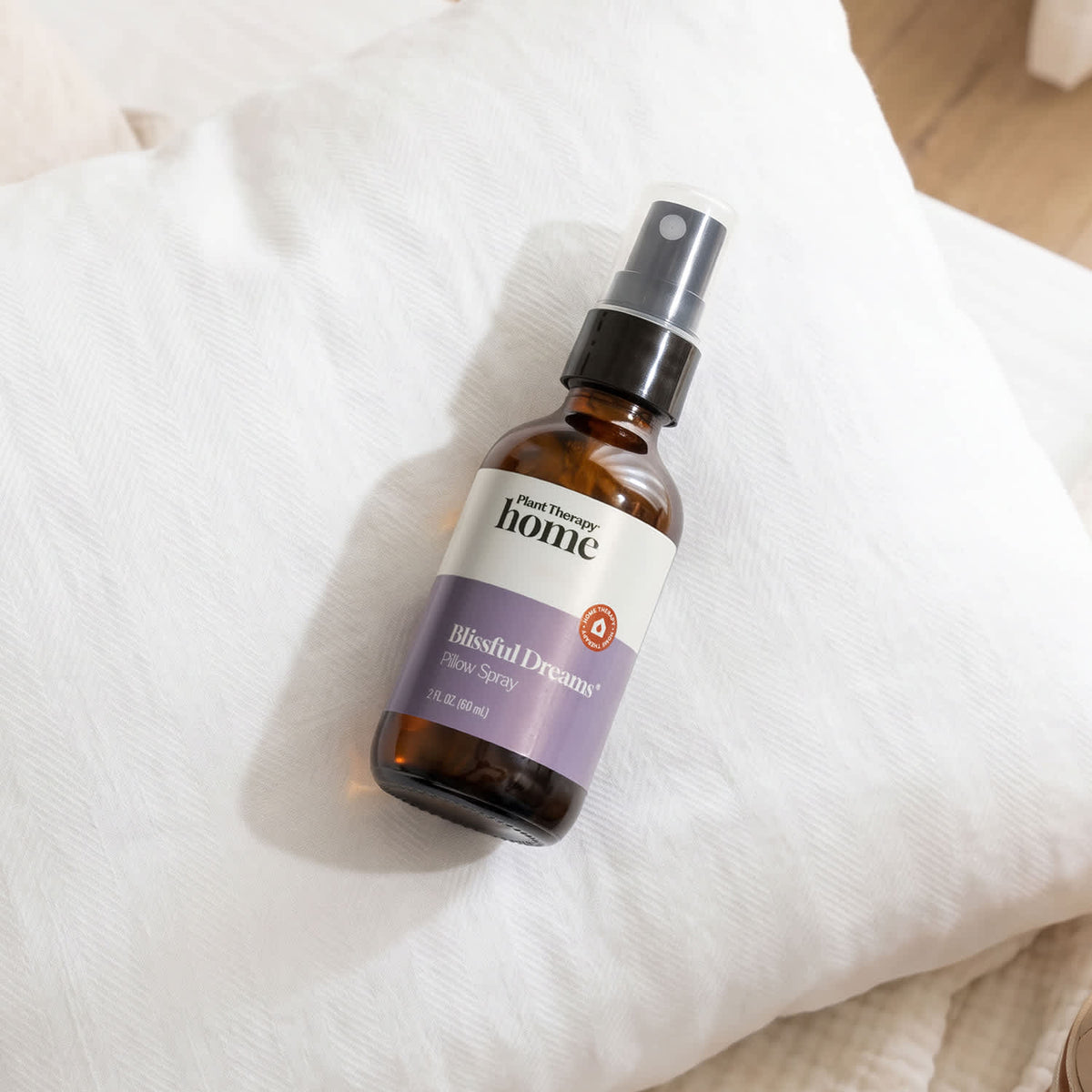 Lavender pillow spray bottle resting diagonally on a textured white pillow