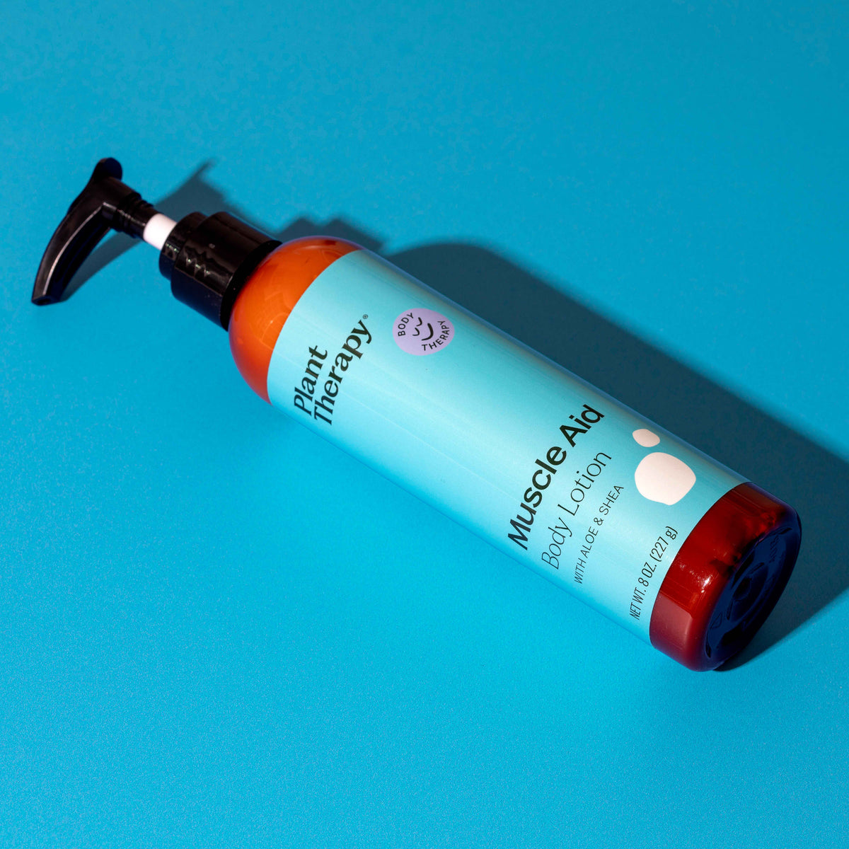 Diagonal amber lotion bottle with black pump on bright blue background