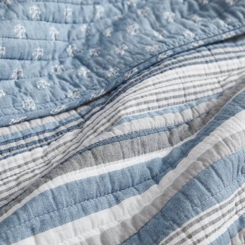 Reversible nautical anchor pattern on blue background next to striped cotton quilt side