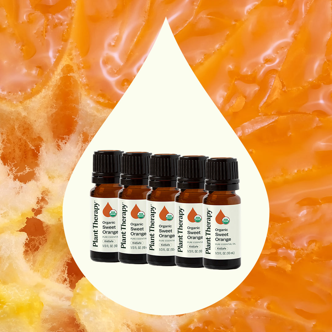 Essential oil bottles inside a white droplet shape against fresh orange pulp background