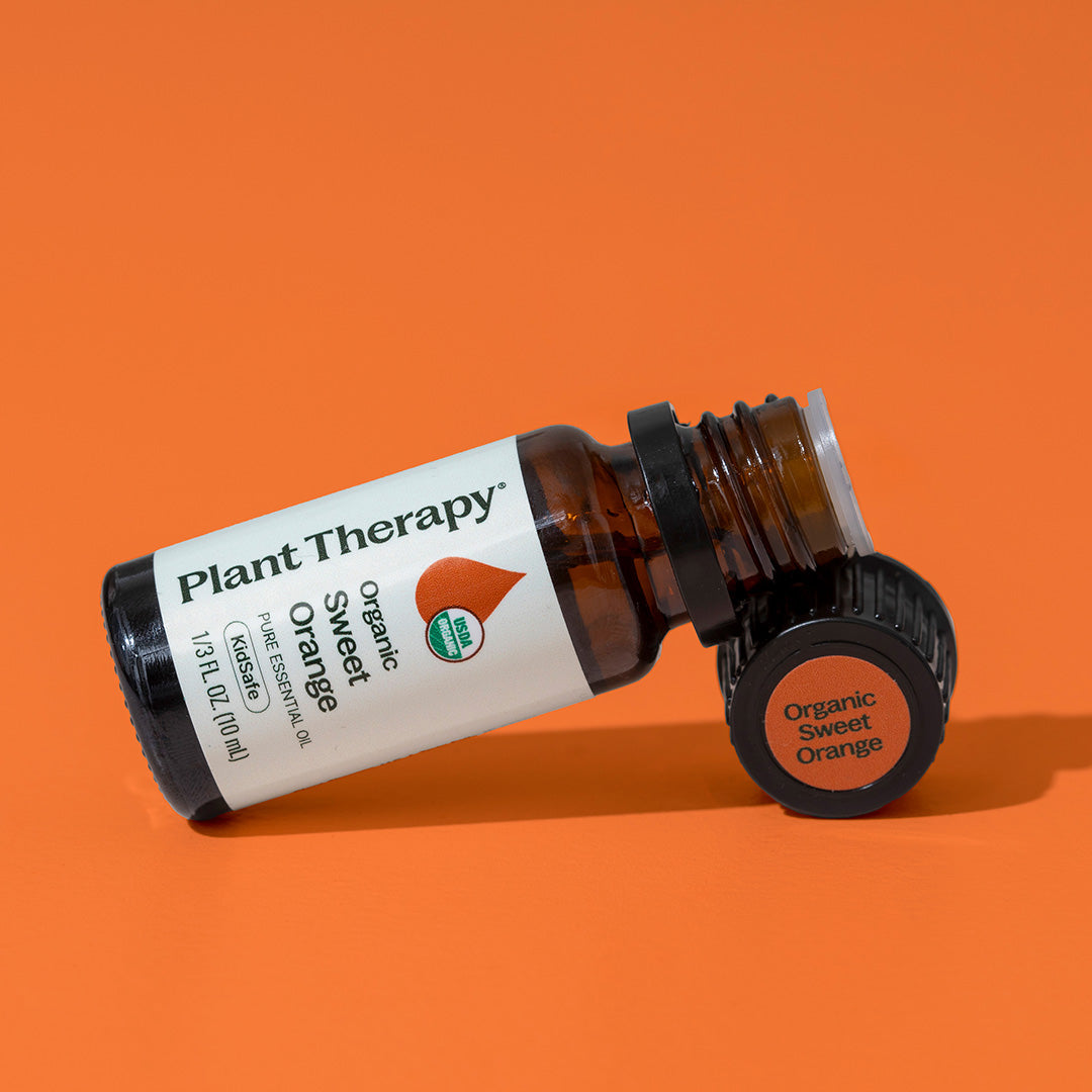 Amber essential oil bottle lying on side with black cap removed showing orange sticker label