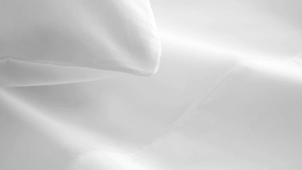 Macro close-up of white organic cotton fabric texture showing fine weave details