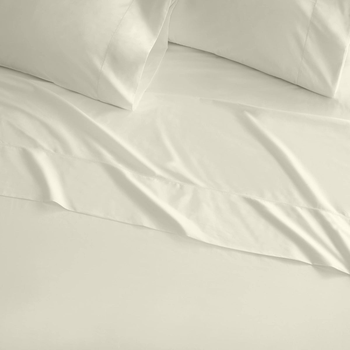 White percale bedding with natural folds and subtle picot embroidery along hem