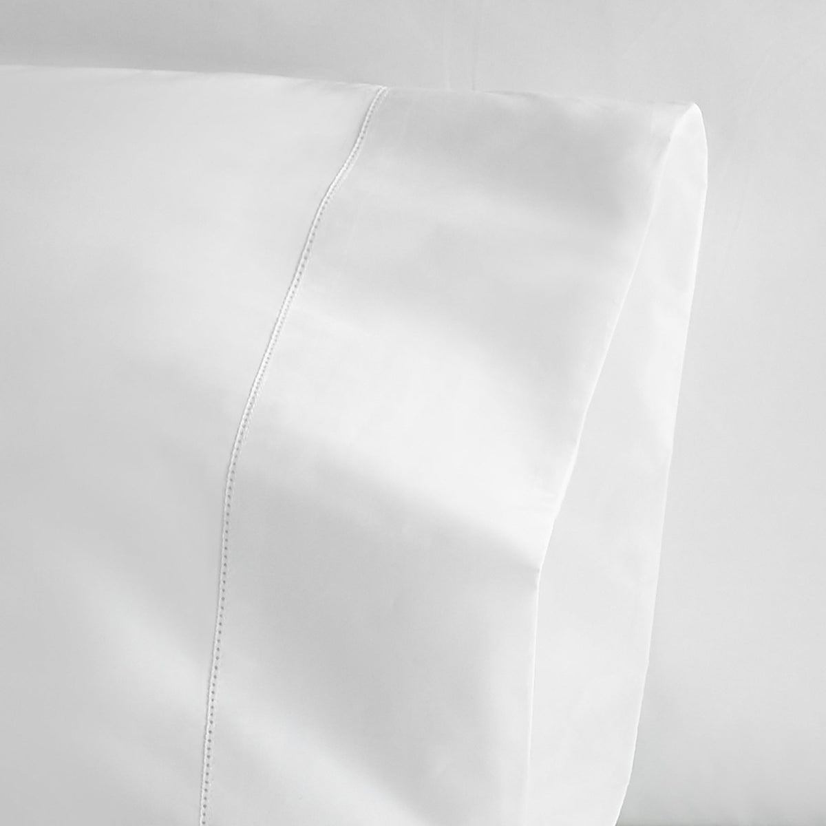 Extreme macro shot of white pillowcase corner showing fine stitching and picot trim