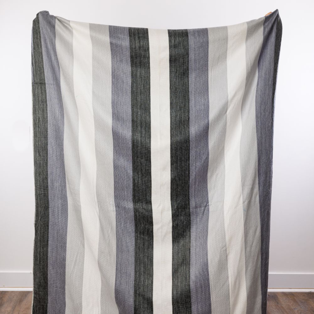 Vertical monochromatic stripe pattern of charcoal and white alpaca yarn held against a white wall