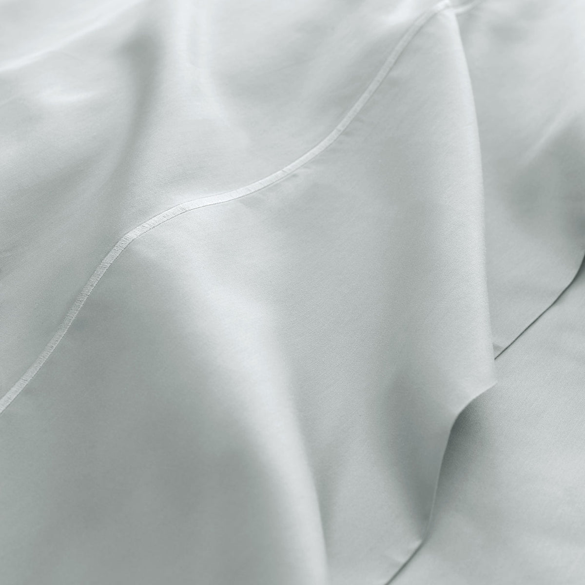 Extreme close-up of white 300TC sateen fabric texture showing smooth silky surface, soft folds, and precise piping