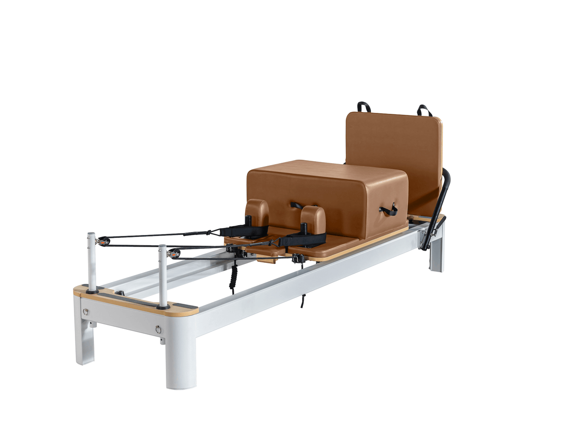White frame Pilates reformer with light wood accents and cognac brown upholstery on plain white background