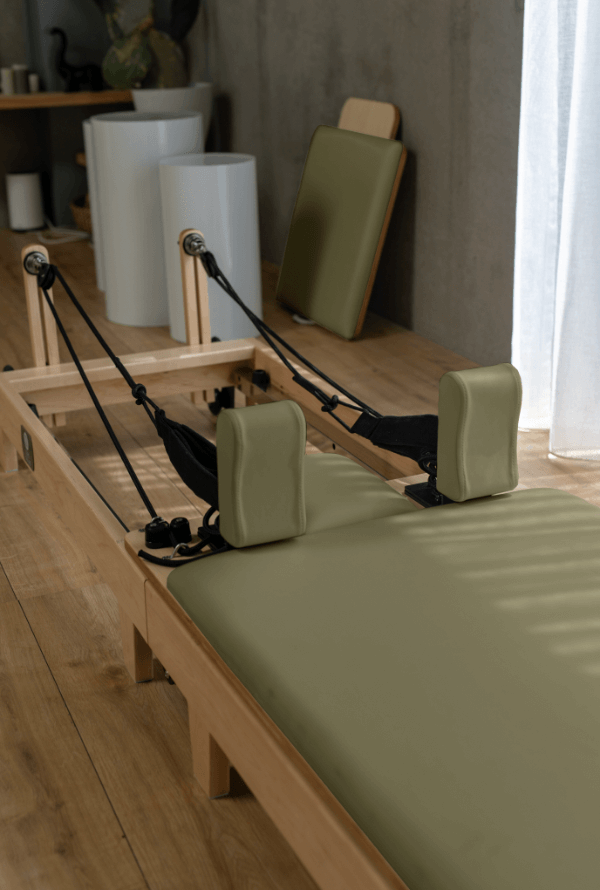 Angled view of sage green carriage and shoulder blocks on solid oak frame against white decor backdrop