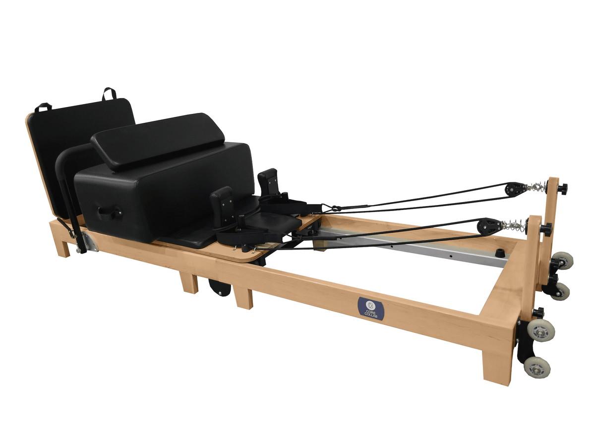 Black upholstery reformer with jumpboard attachment, FSC oak frame, and brand logo isolated on white