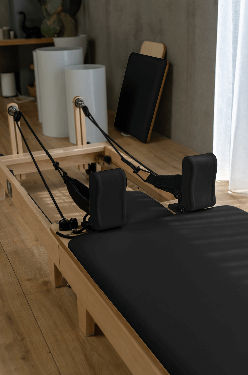 Perspective shot of black leather padding, tensioned ropes, and sturdy wooden frame on light wood floor