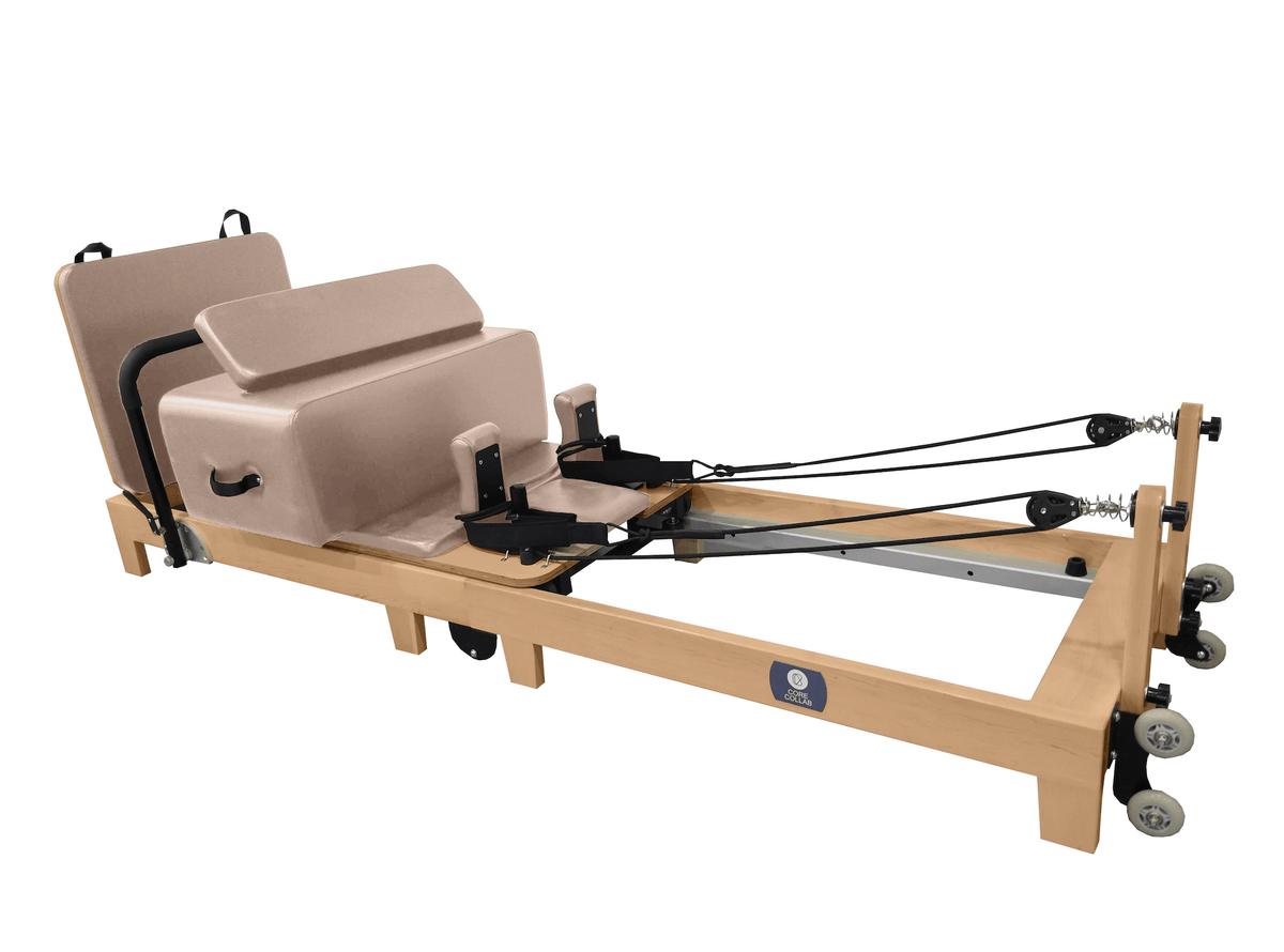 Full shot of pink Eco Folding Reformer showing FSC oak frame, six springs, and blue logo on white background