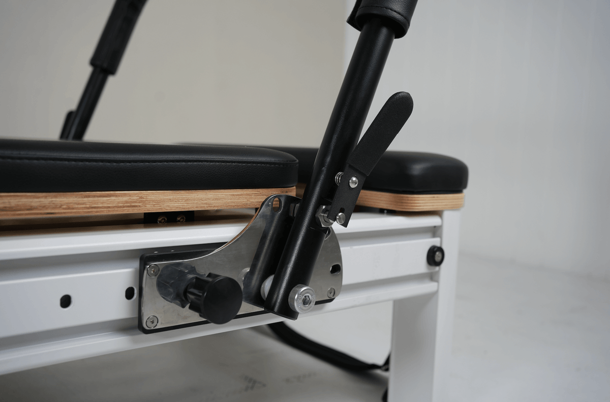 Detail of adjustable black shoulder rest mechanism showing stainless steel pivot plate and layered plywood base.