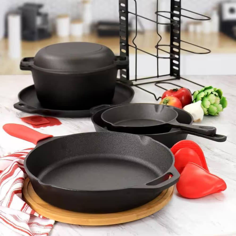 Cast iron cookware set on marble counter with skillet, Dutch oven, red accessories, and vegetables