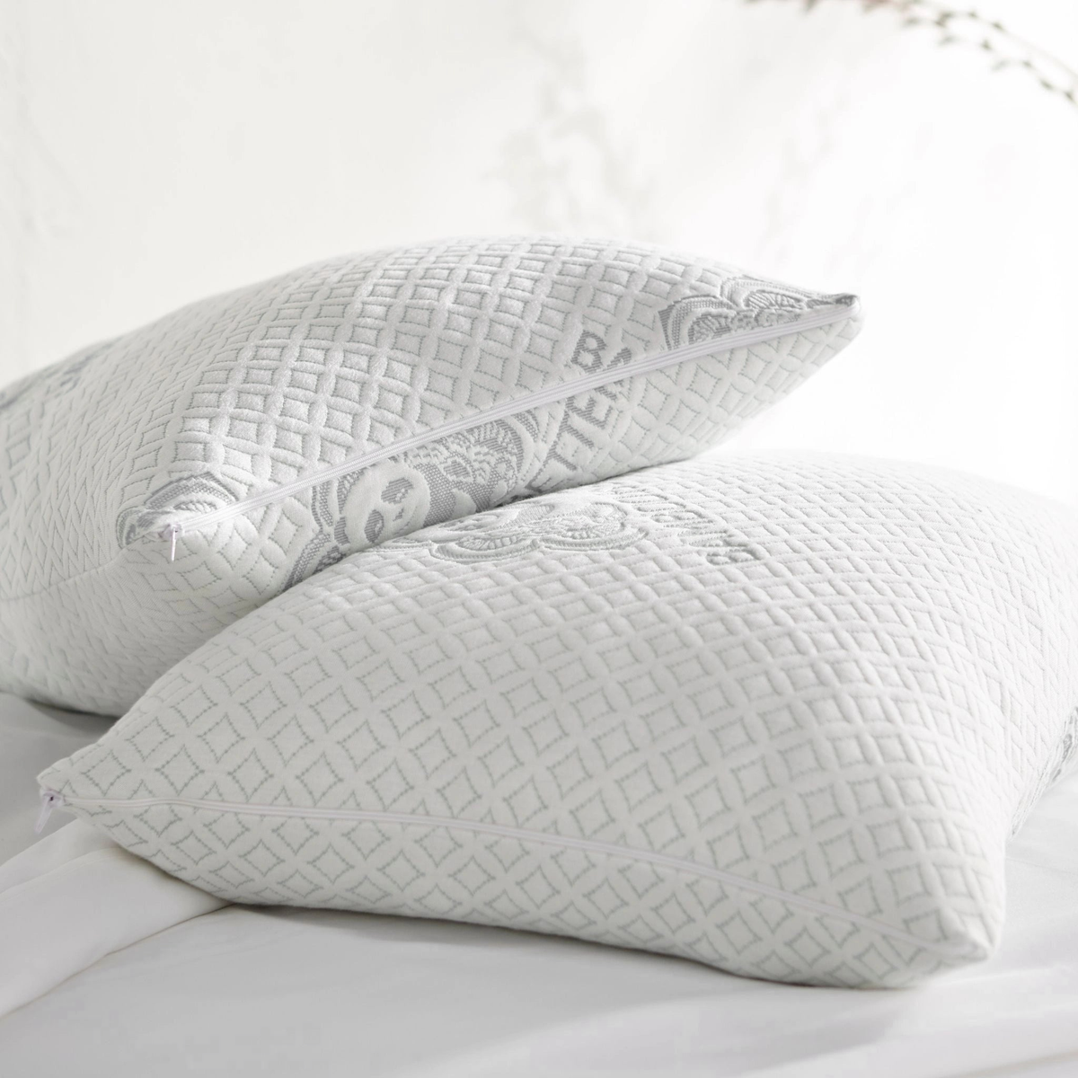 Stacked white adjustable cooling pillows with visible side zipper and grey branding
