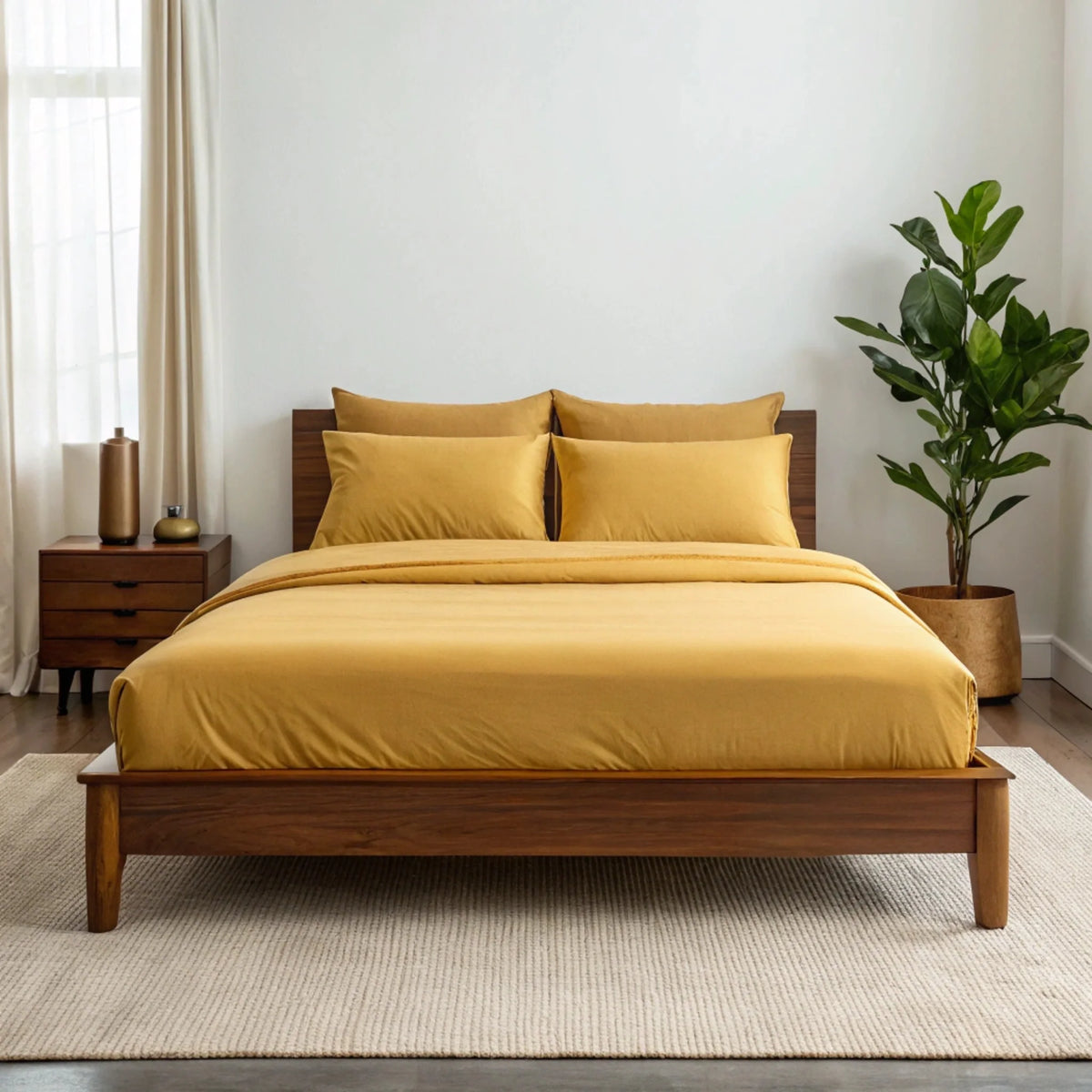 Mustard yellow bamboo sheet set on low-profile wooden bed in bright room with fiddle leaf fig plant and woven rug