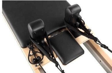 High-angle shot of black padded shoulder rests and adjustable footbar on eco-friendly wooden pilates reformer