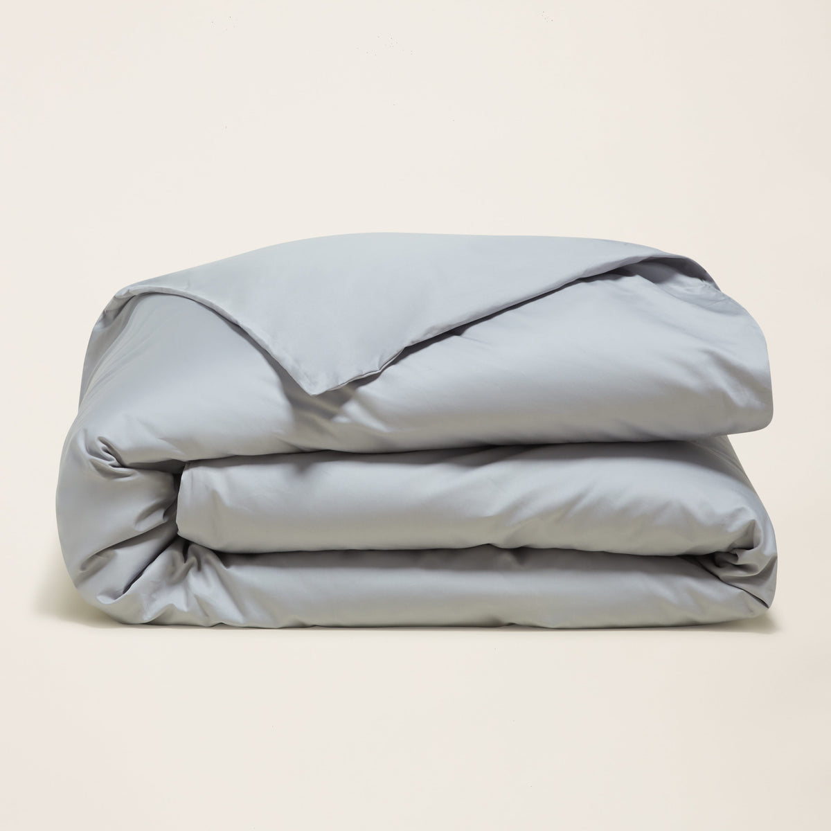 Folded cool grey sateen duvet cover stacked neatly against off-white background