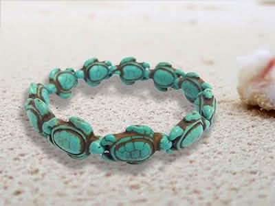 Close-up of carved turquoise turtle charm resting on porous stone next to blurred shell