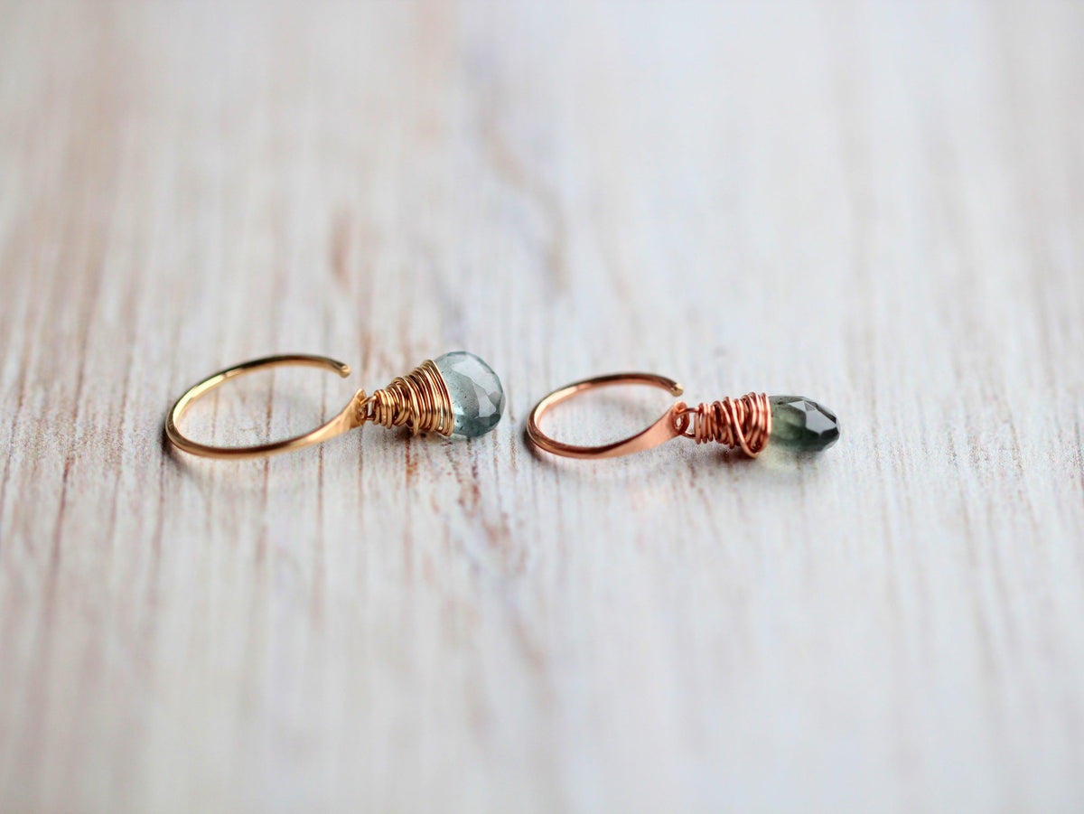 Yellow and rose gold filled hoops with blue-green stones side by side on wood