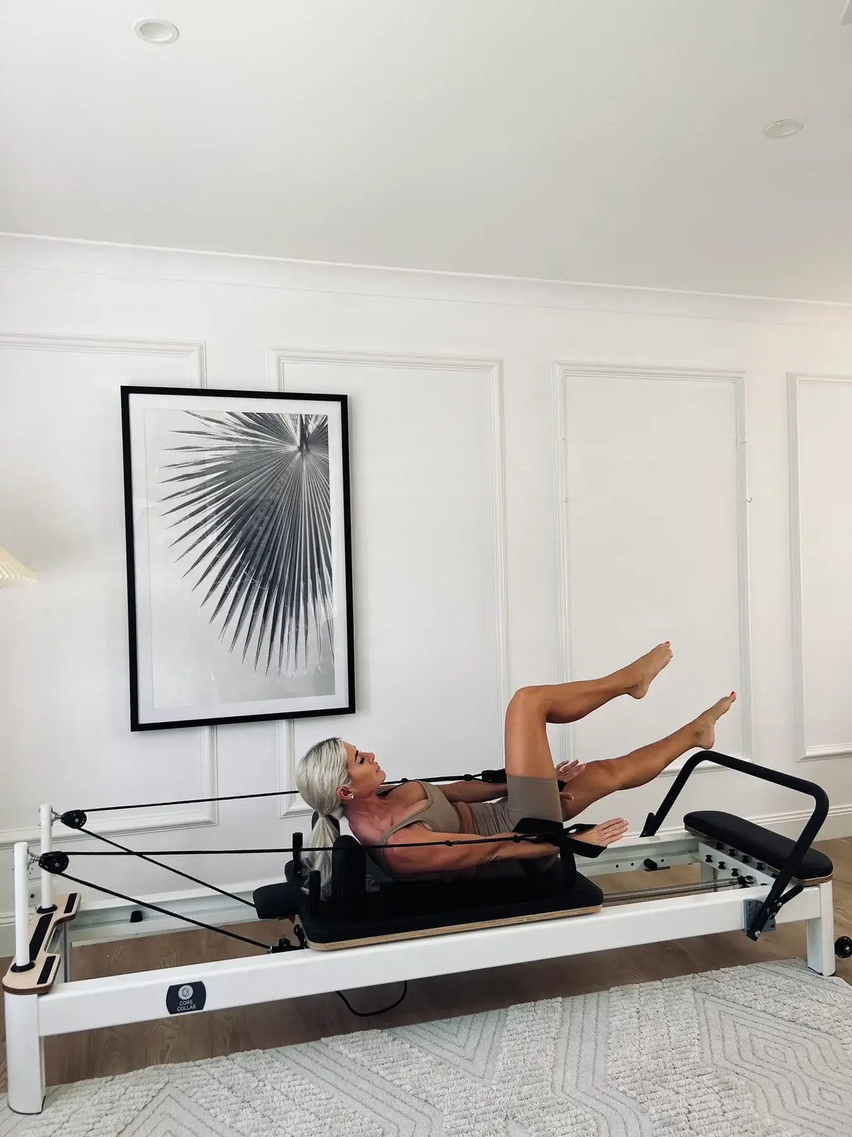 User performing core exercise on reformer showing 'The Core Collab' logo