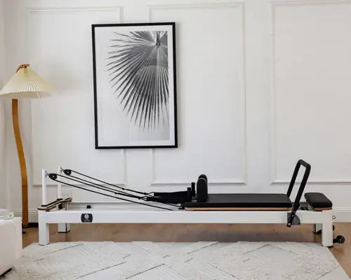 White Queen Studio Pilates Reformer with black padded carriage in minimalist room