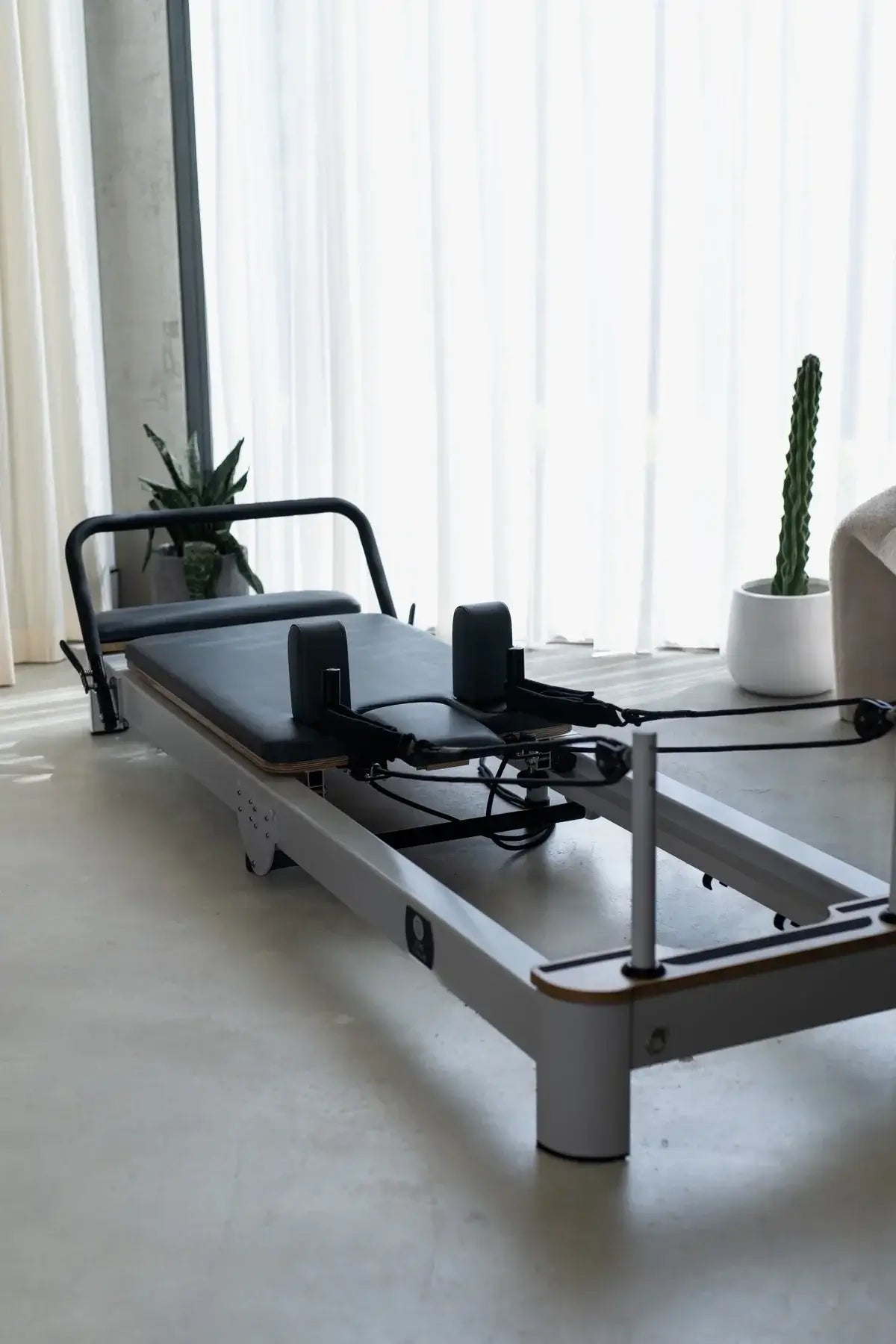Matte white customized pilates reformer with charcoal upholstery in a bright studio setting