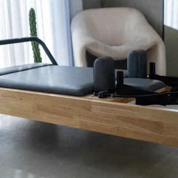 Close-up of black padded carriage and adjustable shoulder blocks resting on sustainable oak wood grain texture