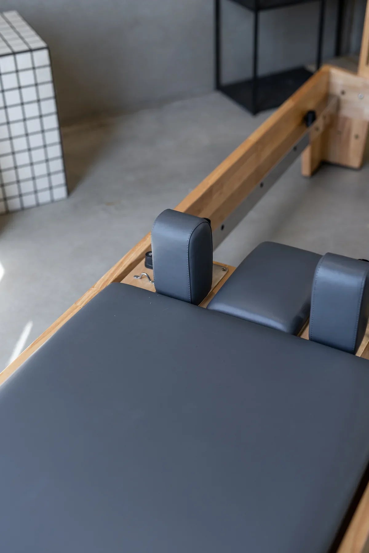 High-angle detail of premium dark grey upholstery texture on carriage contrasting with natural solid oak frame grain