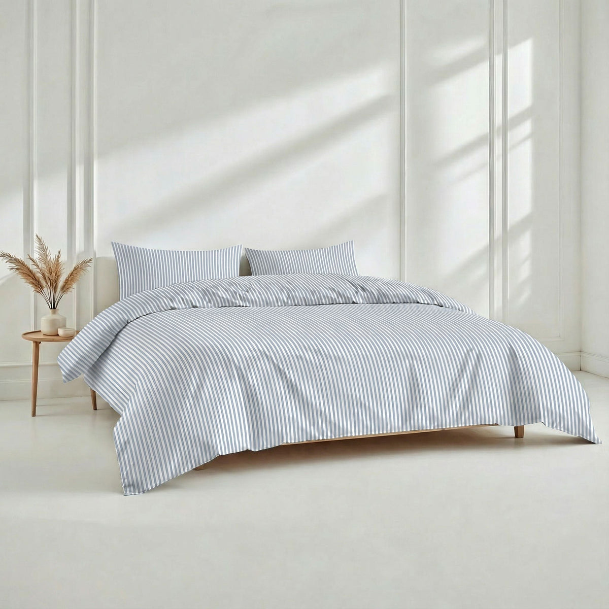 Blue and white striped bedding set presented on a low wooden bed in a sunlit white room